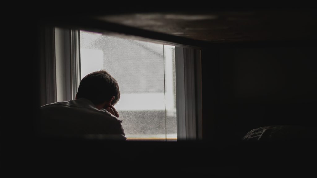 photo of a man looking outside by window